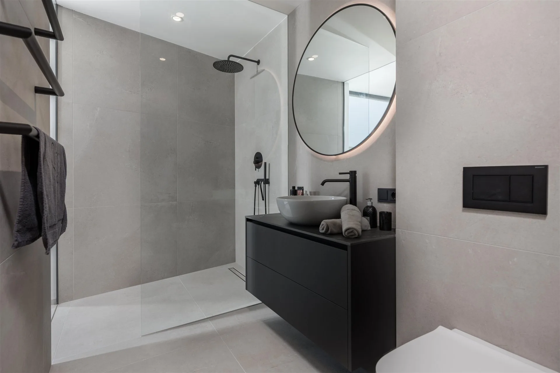Villa Moana en-suite bathroom — round backlit mirror, black vanity and walk-in rain shower