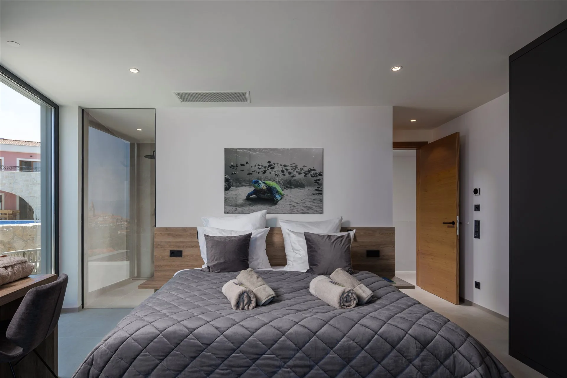 Villa Moana bedroom — handmade oak headboard, art photography, floor-to-ceiling glass