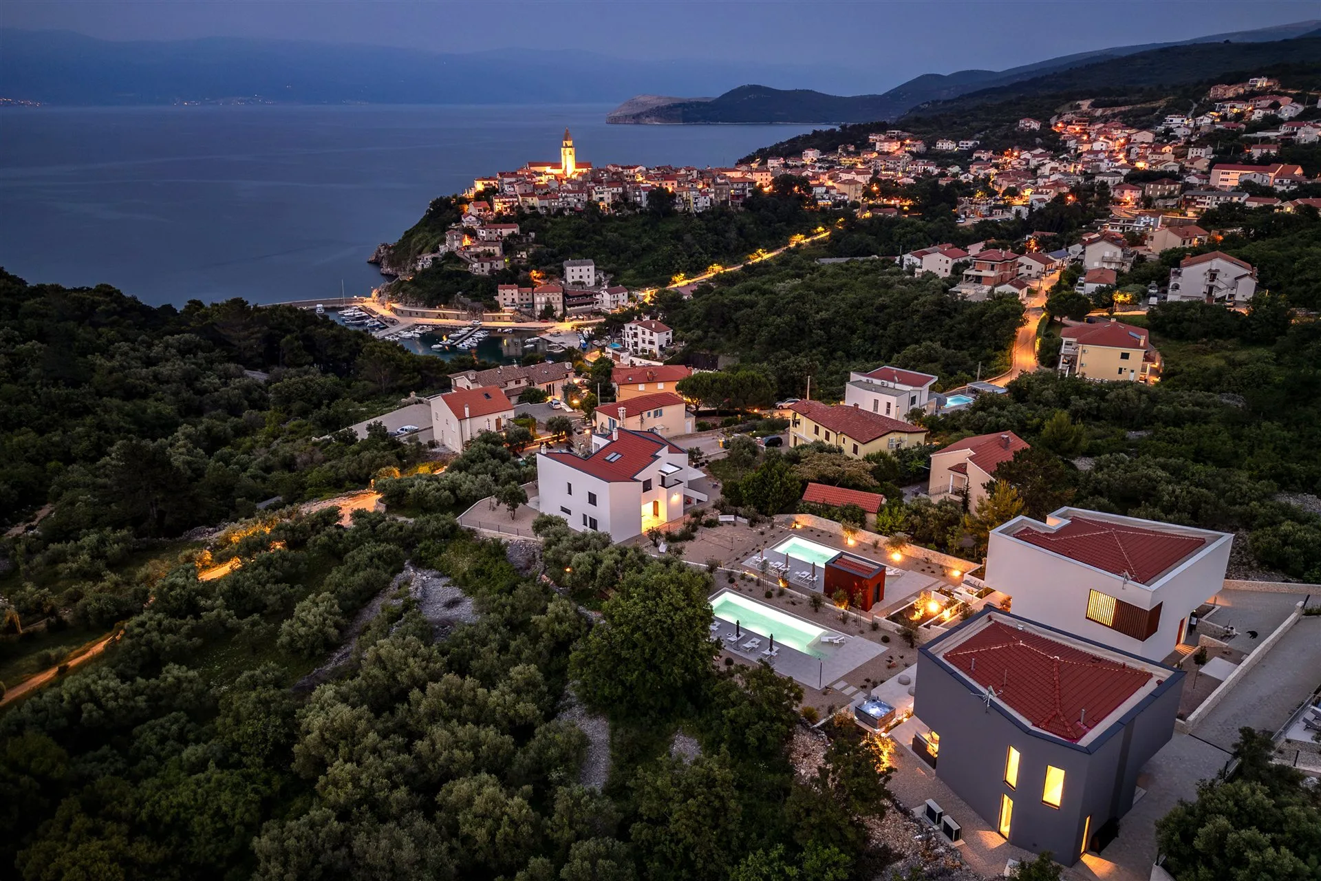 Estate at dusk — both villas with illuminated Vrbnik old town behind