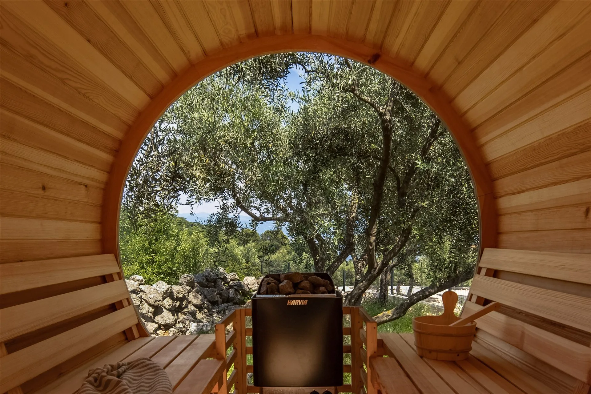 Inside Villa Moana's barrel sauna — circular cedar frame opening onto ancient olive trees